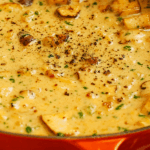 Creamy mushroom sauce simmering in an orange pot with herbs and black pepper