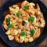 Top view of gambas al ajillo with garlic and parsley in a red skillet