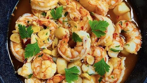 Top view of gambas al ajillo with garlic and parsley in a red skillet