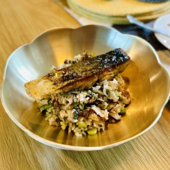 Delicious seared Salmon Pot Rice topped with a crispy salmon fillet and fresh spring onions in a traditional Korean brass bowl.