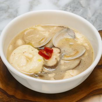 Mild Korean soft tofu stew with perilla seeds clams mushrooms and soft tofu in a white bowl